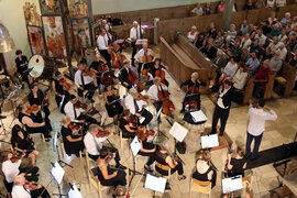 Das Orchester spielt vor Publikum mit einem Violinsolisten in der Neustädter Kirche. 